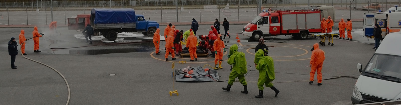 various individuals in hazmat suits performing training exercises outside with fire trucks and ambulances